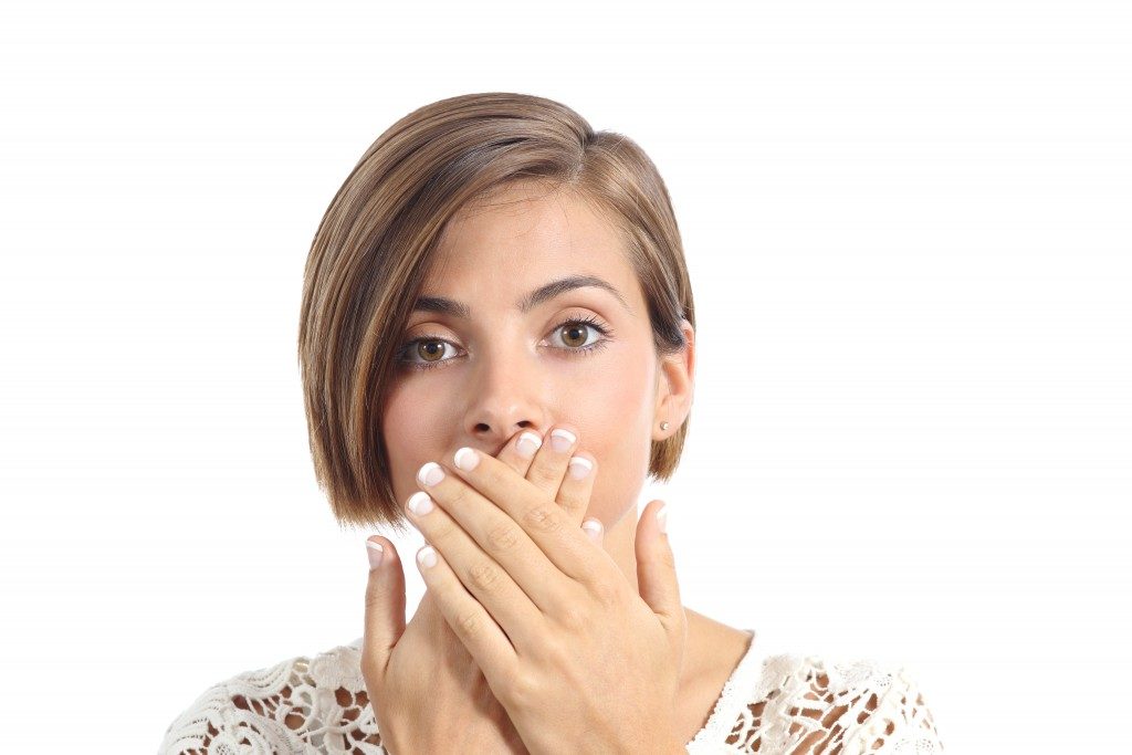 Woman with bad breath covering her mouth