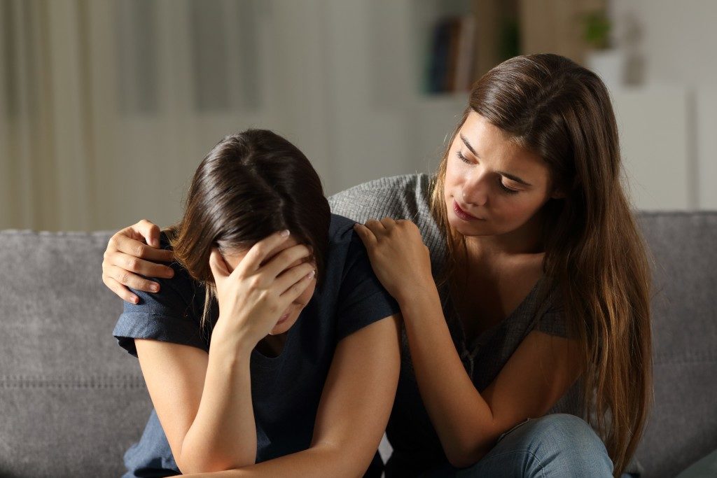woman crying in grief while her friend comforts her