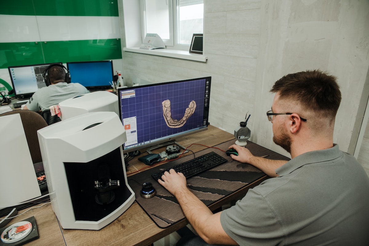 Unrecognizable specialist working on computer in modern dental clinic