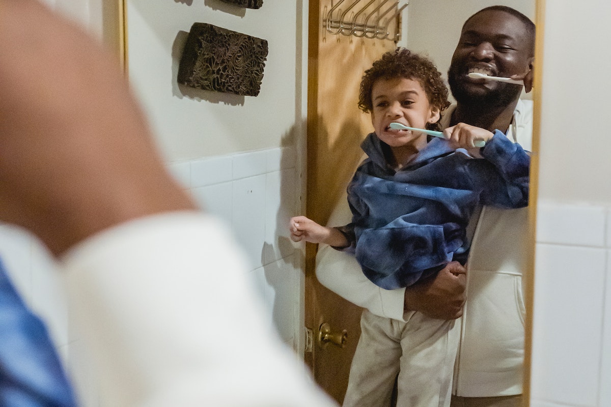 Black father and son brushing teeth in bathroom