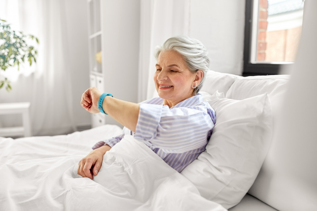 elderly woman happily waking up from good sleep in white bed