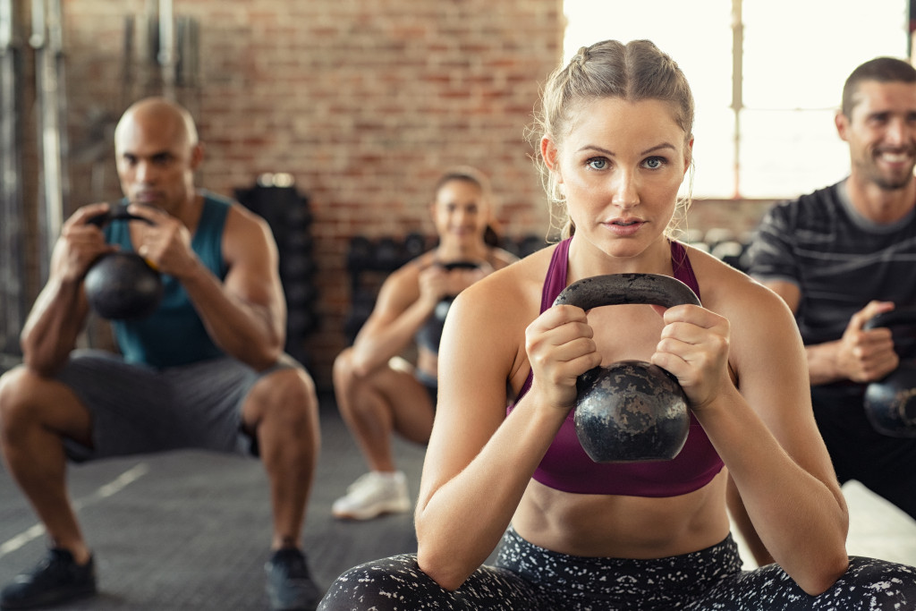 woman exercising at gym with group of people